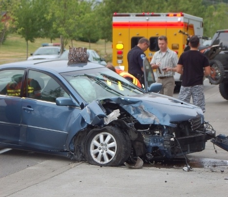 Witnesses talk to officers from the Bremerton Police Department while rescue workers from the Bremerton Fire Department attend to the driver of this Toyota after she crashed into the Kitsap Transit operations building on Charleston Avenue June 15.