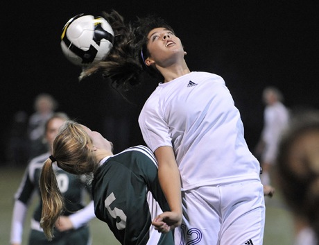 North Kitsap midfielder Ashley Cole wins a header over Port Angeles senior Erin Stockard Tuesday. The Vikings clinched the Olympic League title with a 3-0 victory over the Roughriders.