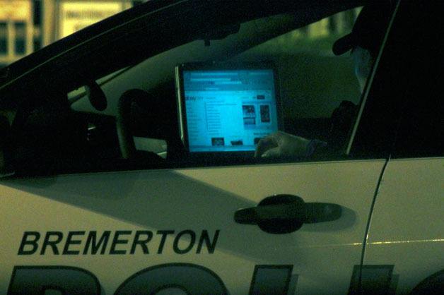 A Bremerton police officer checks out the website eBay Tuesday night while his vehicle sits with the engine running in front of the ferry terminal.