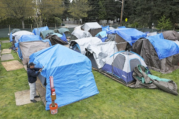 Tent City 4 residents Anthony White secures a tent cover against the wind at the encampment in Kirkland. Advocates hope to create at least two such sanctuaries for the homeless in Kitsap County by this winter.