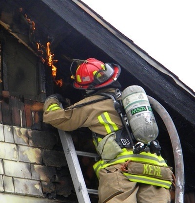 Firefighter Mike Kehl extinguishes residual flames at a Port Orchard house fire on Wednesday.