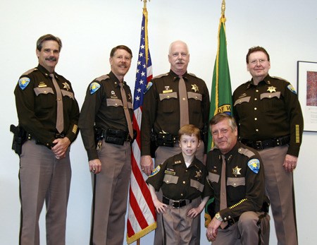 9-year-old Joshua Low is surrounded by Kitsap County law enforcement’s “top dogs.” Low was chosen by the Kitsap County Sheriff’s Office as the “Sheriff for a Day.” Pictured from left to right