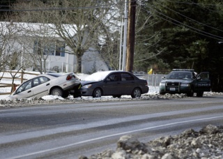 A Kitsap County Sheriff's deputy responds to two cars left behind by their owners on Bucklin Hill Road in Silverdale Monday morning. Local law enforcement responded to several collisions and abandoned cars as more than 3 inches of snow covered the county Sunday evening into early Monday morning. Many local school districts had delayed start times.