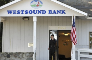 Poulsbo Police officer Nick Hoke talks with other officers at the scene of a robbery at Westsound Bank Tuesday.