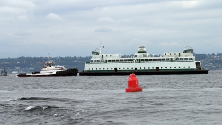 A tugboat guides steel electric ferry Quinault toward Elliott Bay