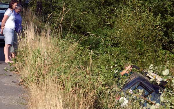 A man hanging out of the driver-side window pulls items from a van