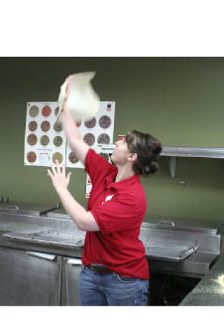 Pizza Time employee Mandy Witty tosses pizza dough into the air at the Bremerton store. Witty’s fiancé