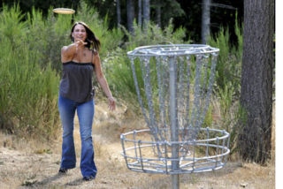 Brad Camp/staff photo Anna Carter of Kingston tosses for a basket at the Kitsap County Fairgrounds disc golf course in Silverdale.