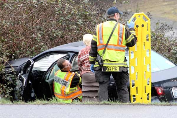 Emergency personnel from the Poulsbo Fire Department assist an injured person (not pictured) in the backseat of a car after a two-vehicle collision on Highway 3 near Thompson Road March 18. The person was sent to Harrison Medical Center.