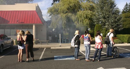 A group of people watches as Dairy Queen employees extinguish a burning bush Tuesday.