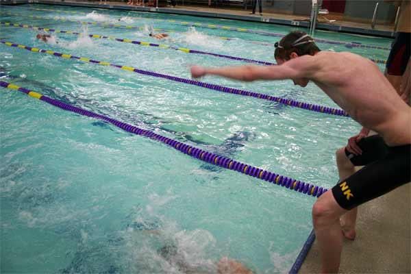 A North Kitsap swimmer shouts encouragements from the edge of the pool to his teammate during the double dual against South Kitsap and Kingston high schools Dec. 18 in the North Kitsap Community Pool.