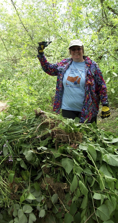 Katha J. Miller-Winder poses with a pile of weeds at a recent Mountaineers clean-up party.