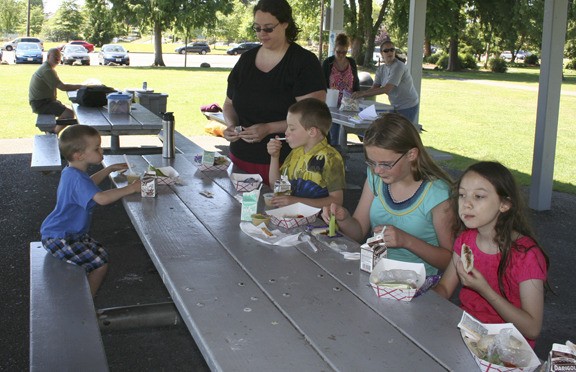 The Grimes family and others enjoy a meal at Evergreen Park in conjunction with the Bremerton School District's Summer Food Program.