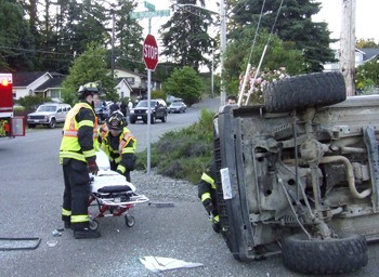 Firefighters prepare to remove the occupants of a Jeep Cherokee that rolled over Monday evening in Lemolo.