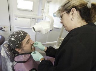 Debbie Schroedle prepares to take an X-ray of veteran Ronald Brown's teeth at the 2008 Kitsap County Stand Down for Veterans where local vets received information and free services