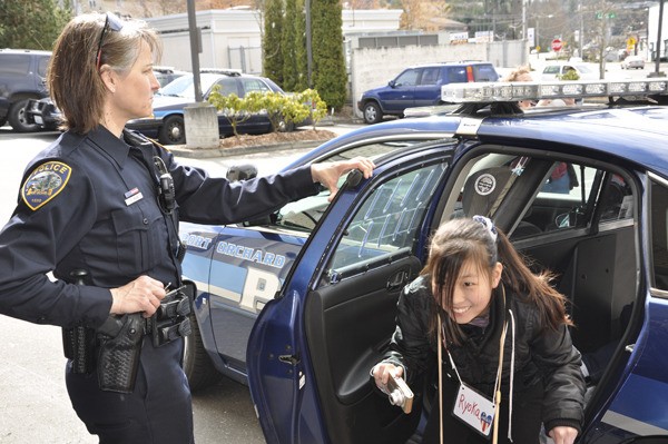 Port Orchard Police Officer Donna Main watches as 12-year-old Ryoka Sato tours a police cruiser.