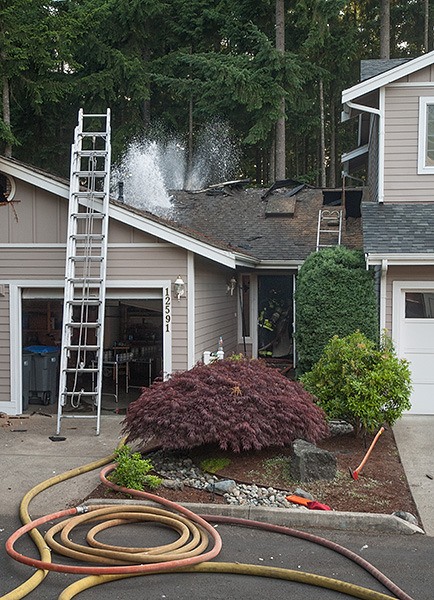 Firefighters spray water up through a hole in the roof of a Silverdale home.