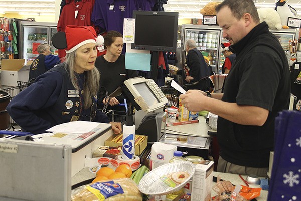 Sherri Burch of the Poulsbo Host Lions Club and TJ Fase of Albertsons check her list to make sure she has all necessary food basket items