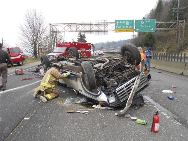 A South Kitsap Fire and Rescue firefighters looks into a truck that rolled over on State Highway 16 on Jan. 19.