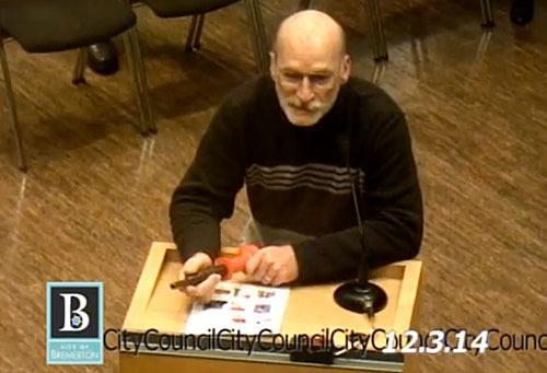 Robert Parker holds a nail gun while addressing the city council about I-594.