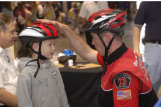 Central Kitsap Fire & Rescue Lt. Greg Platz fits a helmet for a young attendee during Saturday’s event.