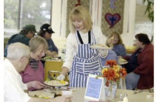 Susan Swanson serves plates of food Wednesday at Silverdale Lutheran Church as part of the Hearty Meals program geared toward lower income citizens.