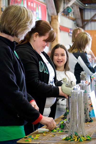 Volunteers Nina Kocourek and April Carmody work alongside fourth-grader Leilani Gray on Tuesday.