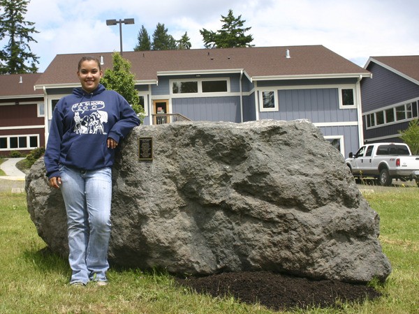 West Sound Academy graduate Liz Leness stands with the 11-ton rock she and her classmates bought and donated to the school. The group of 11 seniors planned to spray paint the rock after their graduation Thursday.