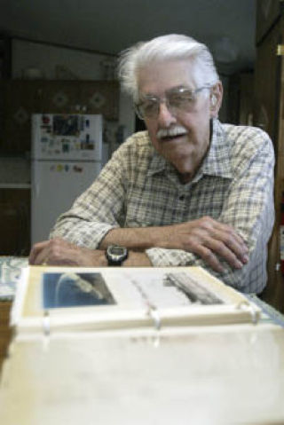 Pearl Harbor survivor Bob Reese looks over a scrap book he put together about his military days.