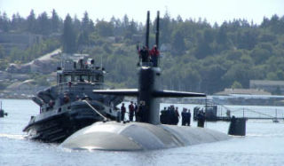 USS Bremerton (SSN-698) is nudged toward Pier Delta at Naval Base Kitsap-Bremerton Wednesday afternoon. The Los Angeles class submarine is visiting Kitsap County for several days