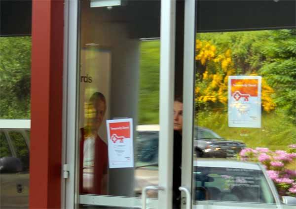 A Key Bank employee at the Poulsbo branch peers out of the front door following an alleged robbery Thursday afternoon. The suspect is thought to be carrying a weapon.