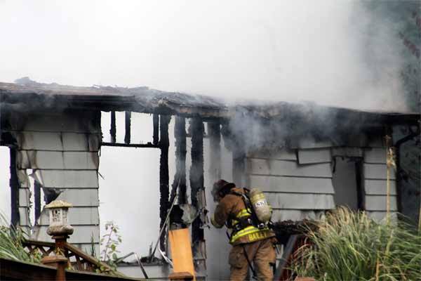 A firefighter from North Kitsap Fire & Rescue prepares to enter a home off Twin Spits Road as emergency crews continue to douse flames that destroyed the  structure Dec. 5.