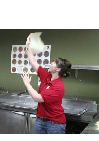 Pizza Time employee Mandy Witty tosses pizza dough into the air at the Bremerton store. Witty’s fiancé