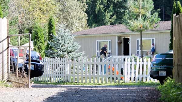 A narcotics investigator with a camera enters a house on Finley Road near Poulsbo