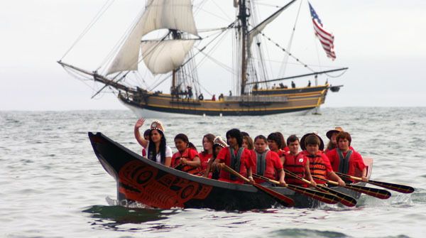 2012-13 Miss S'Klallam Days Andrea Ashworth waves as the Port Gamble S'Klallam canoe arrives Aug. 1 at Quinault's Point Grenville during the 2013 Canoe Journey/Paddle to Quinault. In the background is one of the tall ships that escorted canoes along the Pacific Coast of Washington to commemorate the 225th anniversary of first contact between the new United States of America and the Quinault Nation.