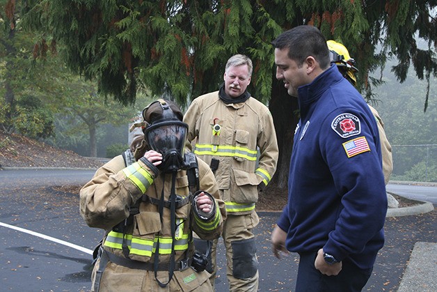 Reporter Seraine Page adjusts her gear as firemen Ronny Smith and Eric Keim look on.