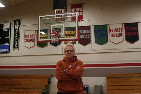 Barry Janusch poses in front of the gymnasium banners following the team’s practice Dec. 9. Janusch