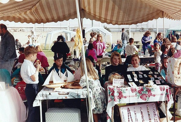 Young vendors sit behind their booths at the Kingston Farmers Market in the early 1990s.