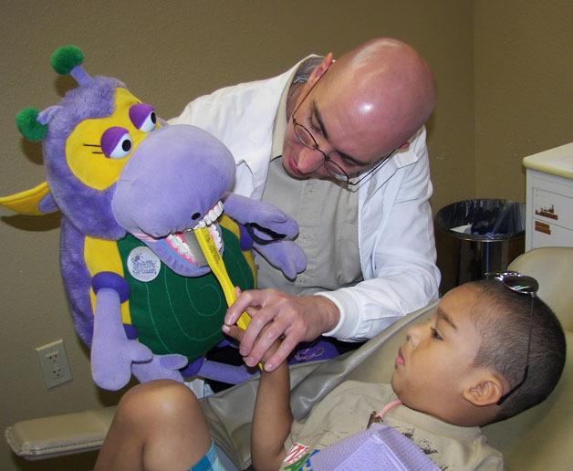 Dr. Lucas Trerice educates a patient on proper brushing technique Tuesday in Tacoma.