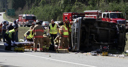 An aid crew removes a crash victim from an overturned van on State Route 3 north of Poulsbo Friday.