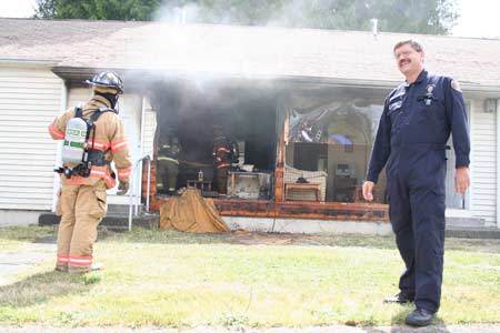 Kitsap County Fire Marshal David Lynam addresses a crowd June 26 after local agencies conducted the first half of a home fire sprinkler demonstration in an old Westpark unit in Bremerton.