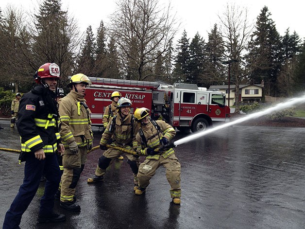 Two Olympic High School students man the hose as Lt. Justin Brown and Paramedic Terrence Lofgreen supervise.