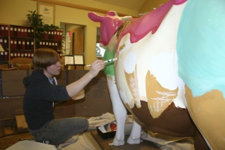 Madeline Trower paints a music-and-ice-cream design on her cow in the lobby of the front office at West Sound Academy.