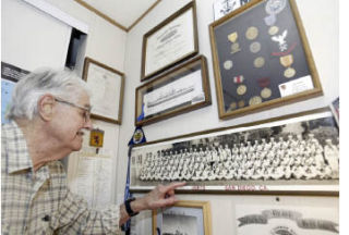 Pearl Harbor survivor Bob Reese looks for himself in a picture from his military days when he was stationed in San Diego.