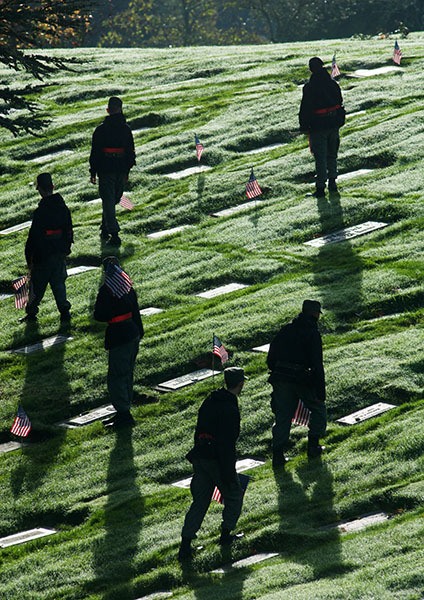 Cadets with the Washington State Academy slowly and silently place flags on the graves of veterans buried at Miller-Woodlawn Memorial Park in Bremerton on Nov. 8.