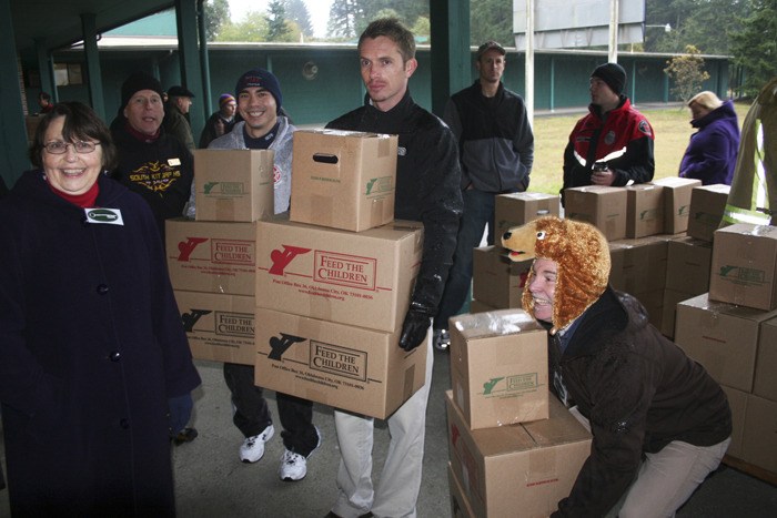 Volunteers carry food boxes distributed to local families Wednesday through the international Feed the Children program. A truckload of food was delivered to the South Kitsap School District food service center on Madrona Drive