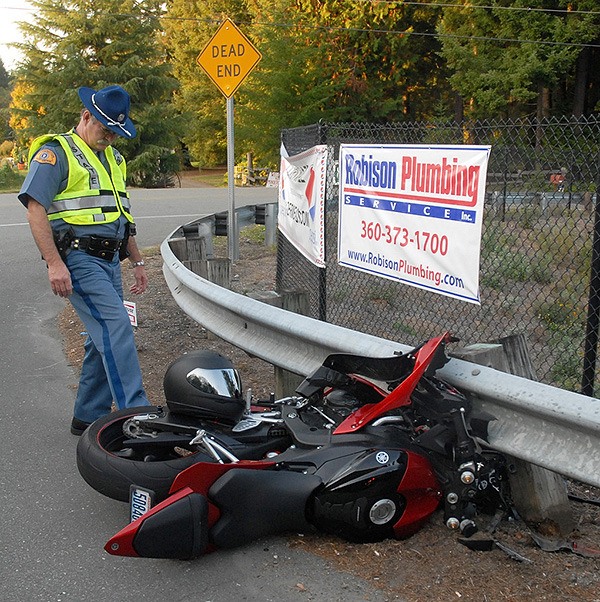 Washington State Patrol Trooper Manning spins the rear wheel of a crashed motorcycle at the intersection of NW Waaga Way and NE Gluds Pond Road in Central Kitsap Oct. 5