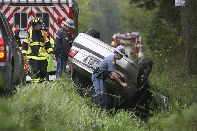 State Patrol Troopers and firefighters inspect a wrecked Saturn Friday on State Route 305.