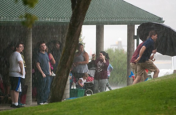 Attendees at the Whaling Days festival in Silverdale take shelter at Waterfront Park as heavy rain falls July 26. The monsoon-like rainfall forced the Jimmy Hendrix cover band that was playing at the time to stop. The lead singer