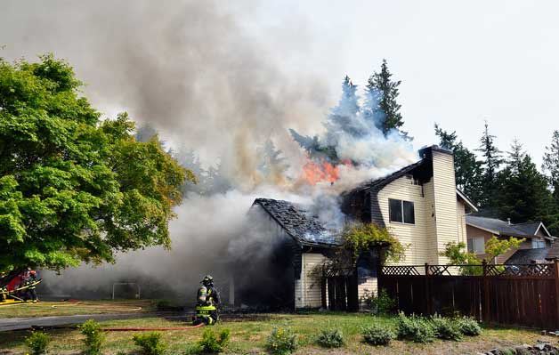 A firefighter works to put out a house fire in the 7000 block of Fidalgo Court NW June 1.